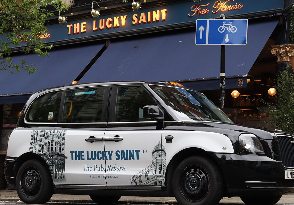 Taxi Supersides advertising on a electric taxi outside of the Lucky Saint pub.